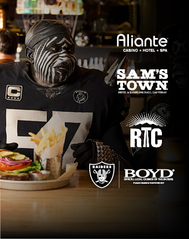raiders fan eating with Aliante, Sam's Town, RTC, Raiders and Boyd logos
