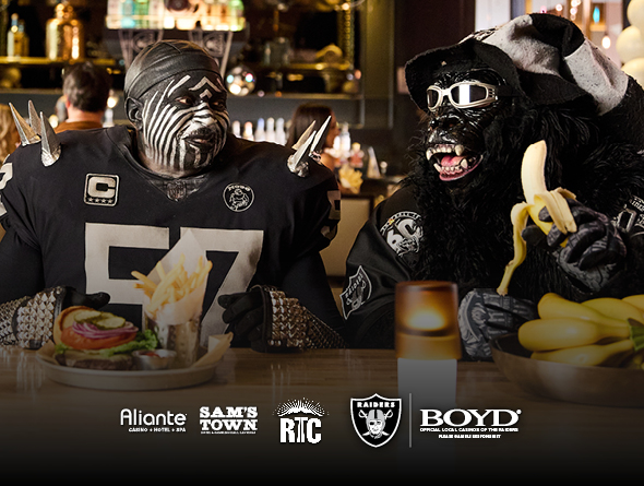 raiders fan eating with Aliante, Sam's Town, RTC, Raiders and Boyd logos