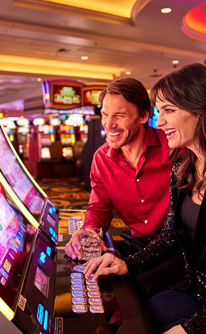 couple sitting at slot machine playing game