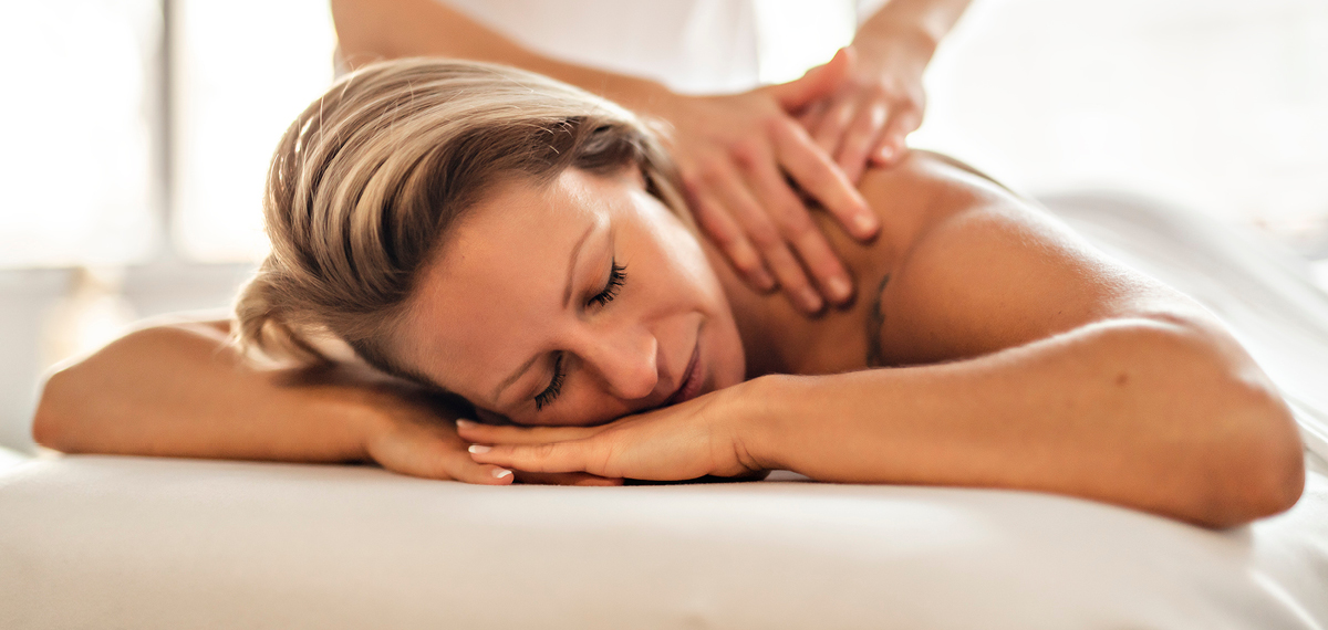 A woman lying on a massage table while a massage therapist gently works on her back, creating a calm and relaxing atmosphere.