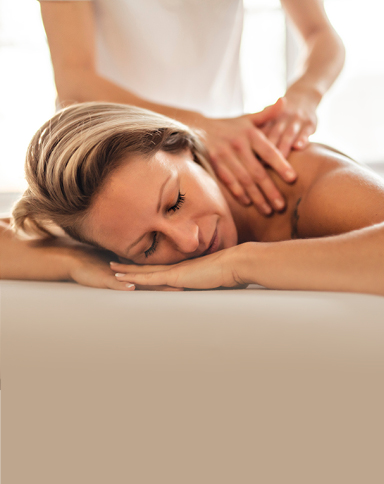 A woman lying on a massage table while a massage therapist gently works on her back, creating a calm and relaxing atmosphere.
