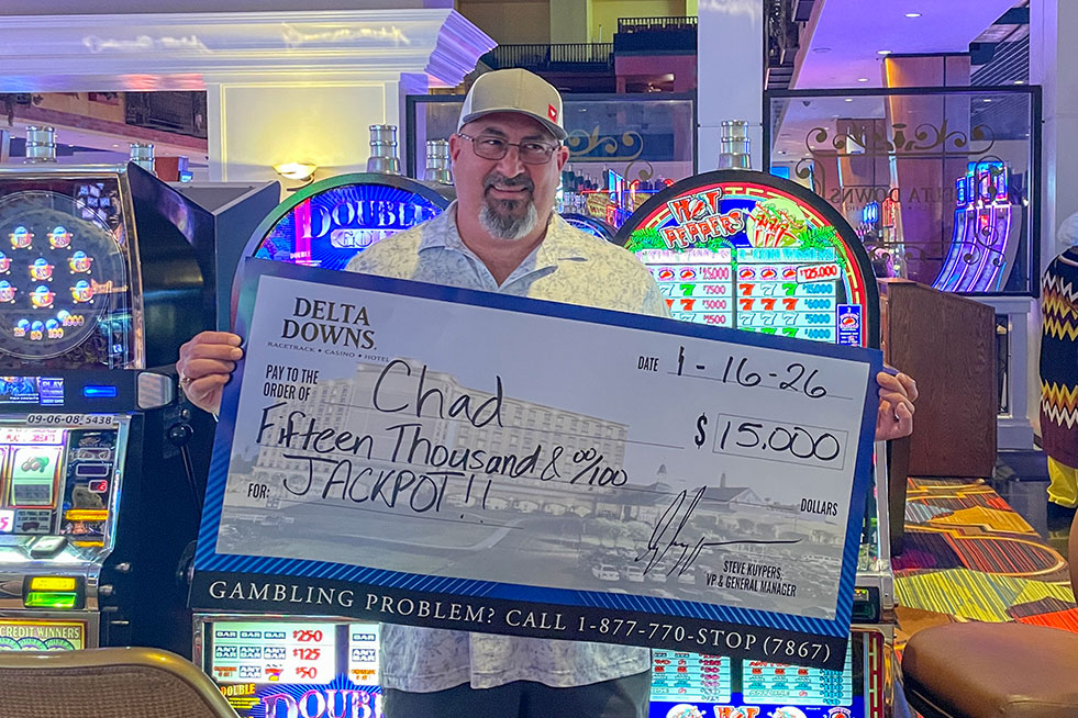 lucky winner in front of a slot machine with a check at delta downs