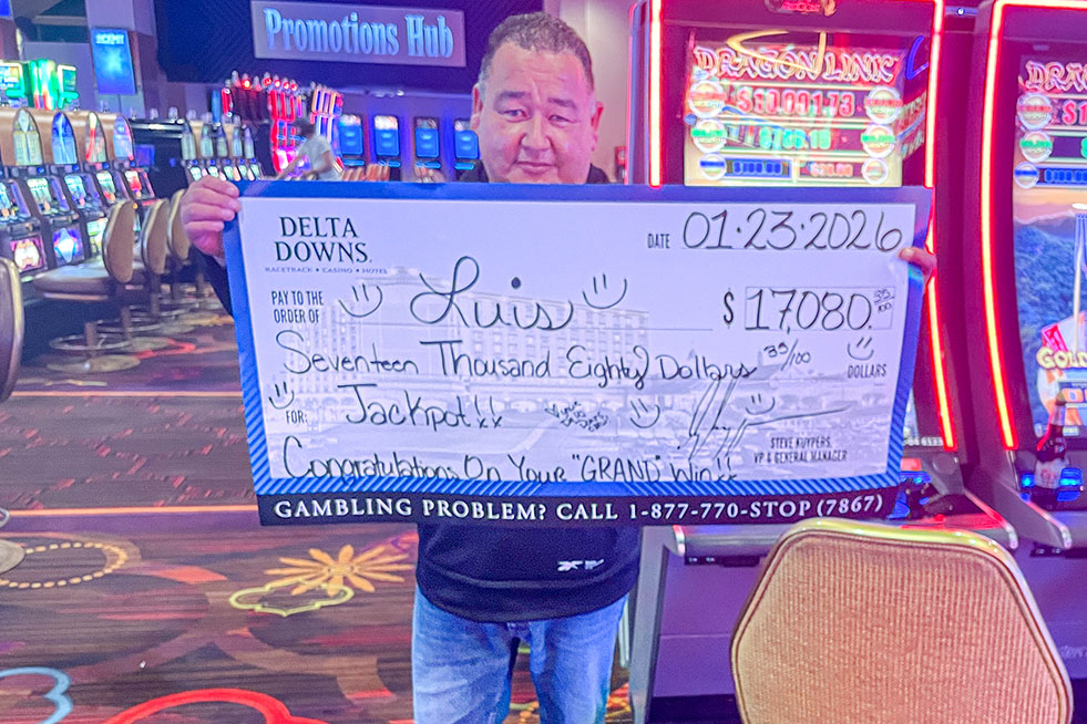 lucky winner in front of a slot machine with a check at delta downs