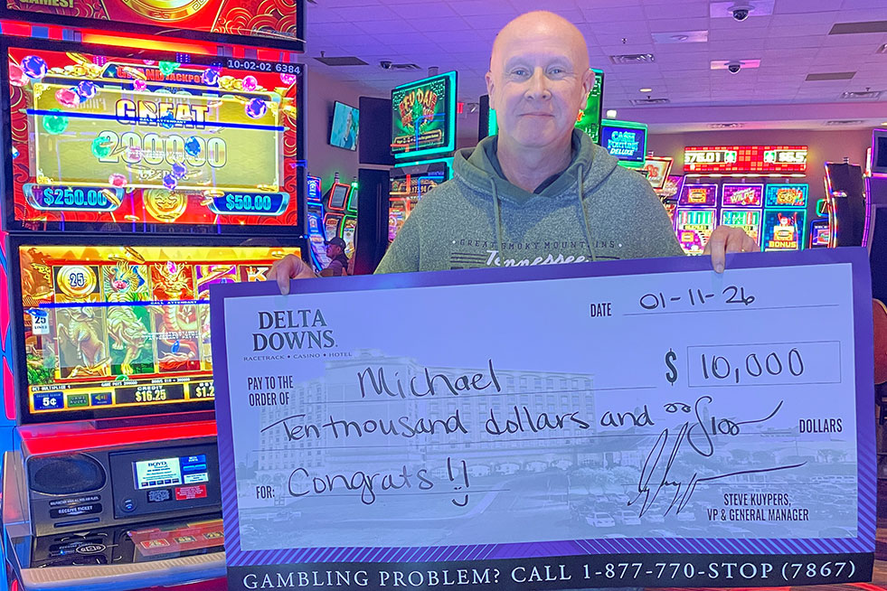 lucky winner in front of a slot machine with a check at delta downs
