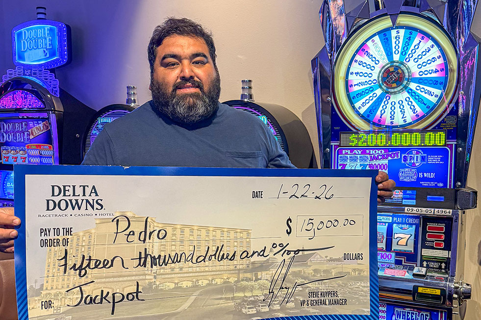 lucky winner in front of a slot machine with a check at delta downs