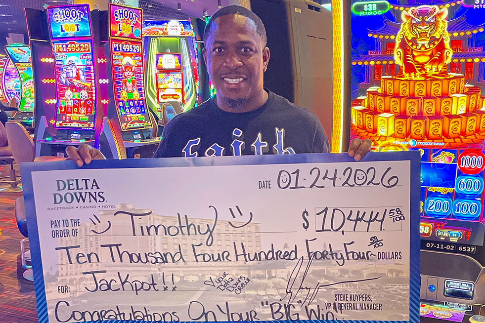 lucky winner in front of a slot machine with a check at delta downs