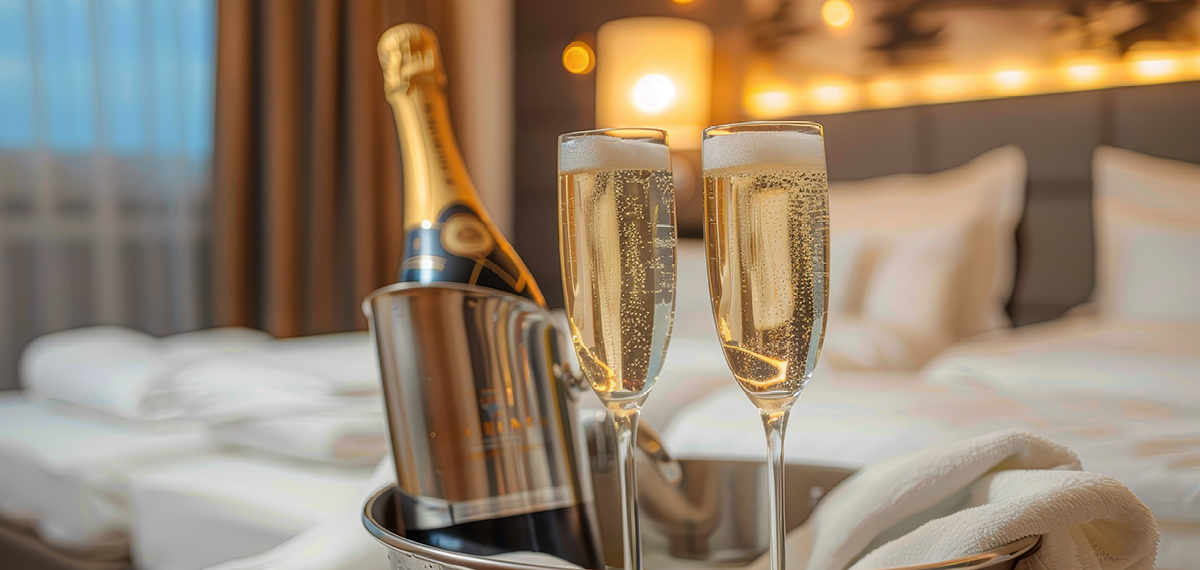 two glasses of champagne on a hotel bed