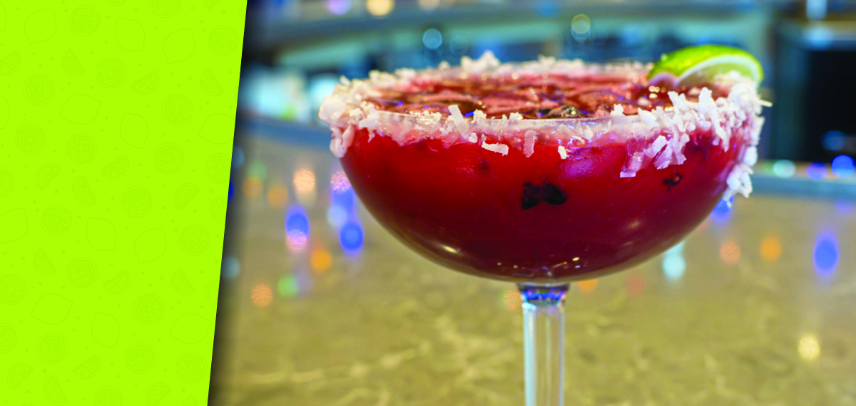 A blackberry coconut margarita garnished with fresh berries and coconut flakes.