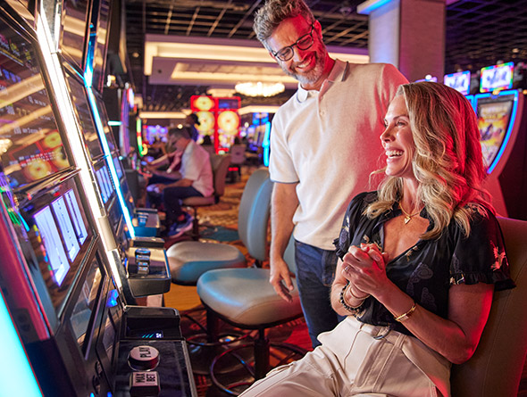Woman playing slots with man smiling at her
