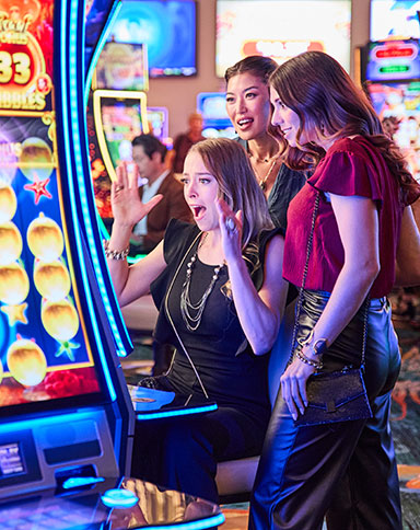 three women playing slots and smiling at a Boyd casino